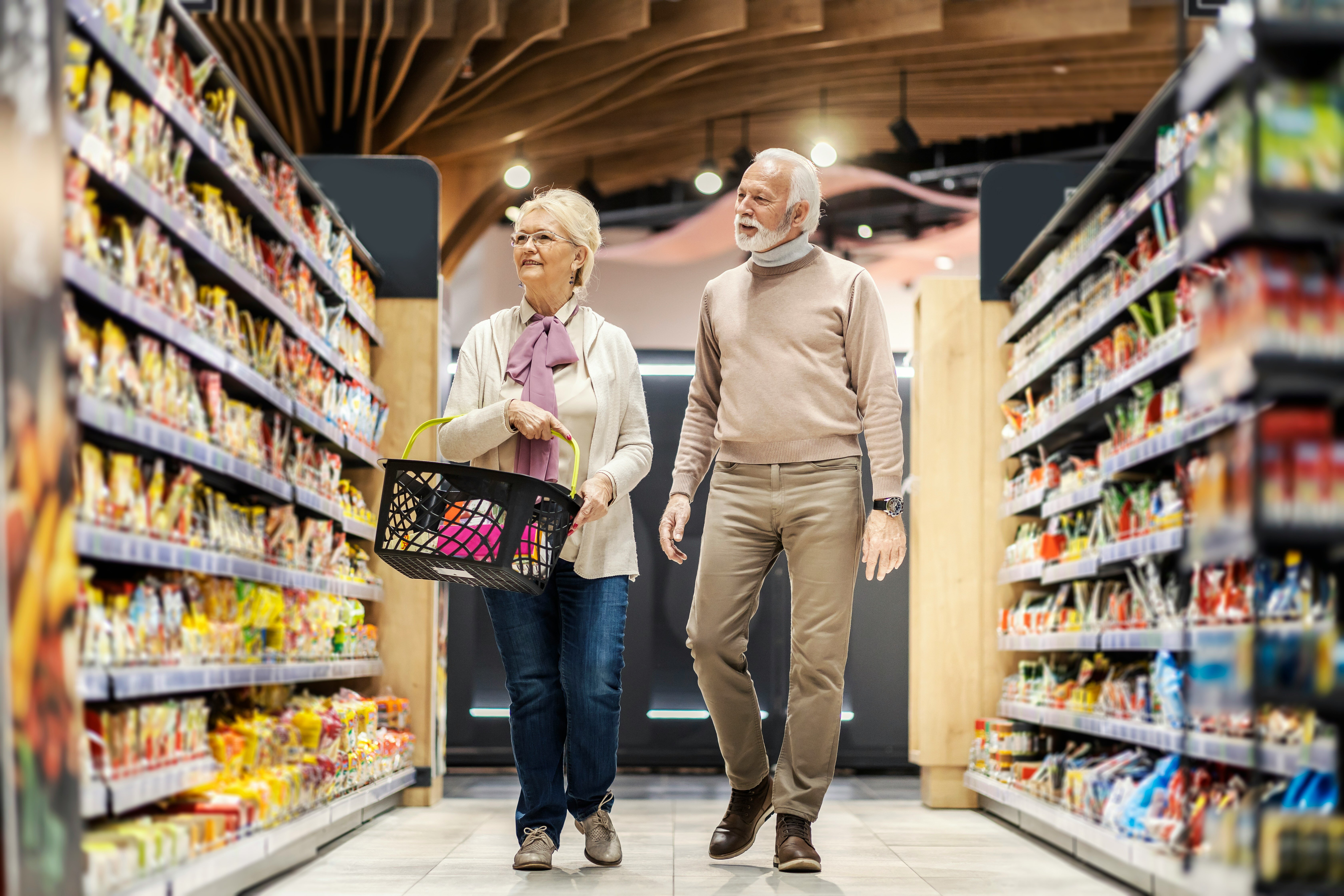 elderly couple walking through grocery store aisles 